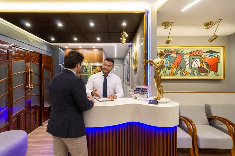 Iago atende um paciente no balcão da recepção da Prime Medical Center.